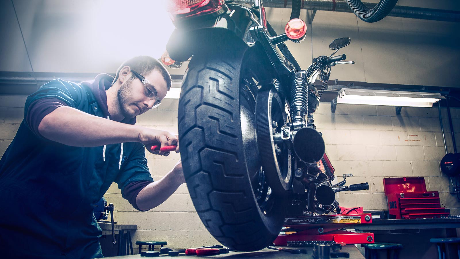 A mechanic attending to a motorcycle on a workshop lift